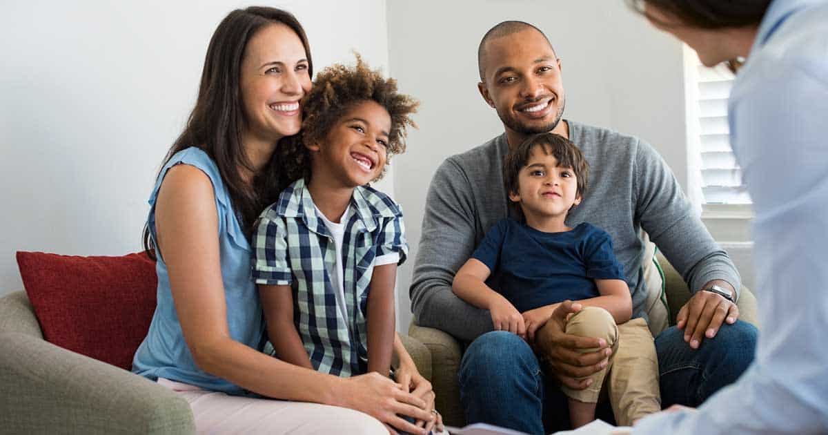 Mixed race family of four sitting with a food allergy counselor on how to handle the mental stress of food allergies.